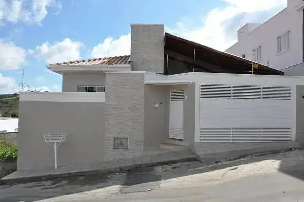 Fachadas de casas térreas: portão branco com parede de pedra (projeto: Cláudia Breias)