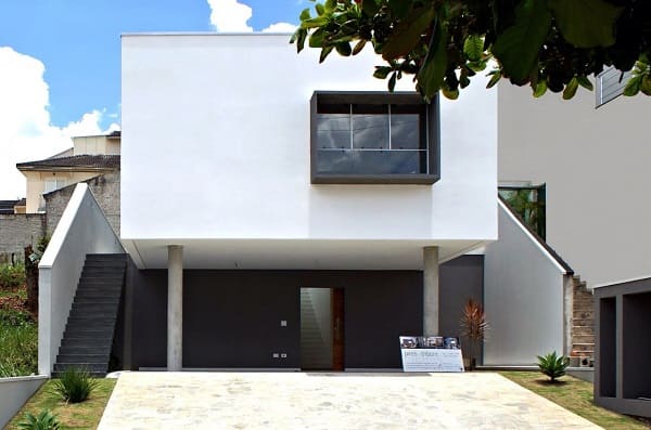 Casas quadradas modernas pequenas: fachada branca com janela preta e pilotis (projeto: Cezar Augusto Pires)