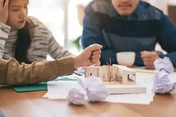 Pré-Obra: Arquitetos trabalhando em um projeto, e em cima da mesa uma maquete (Adobe Stock Photos)