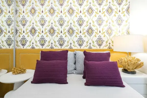 Cores complementares: cabeceira amarela e almofadas roxas (foto: Blog de Decoração Lolahome)