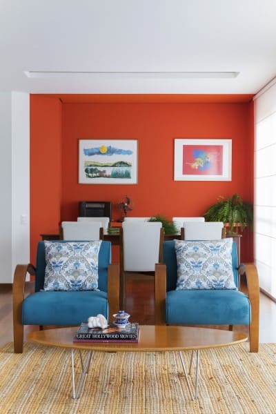 Cores complementares: parede laranja e poltrona azul (projeto: MIS Arquitetura e Interiores)