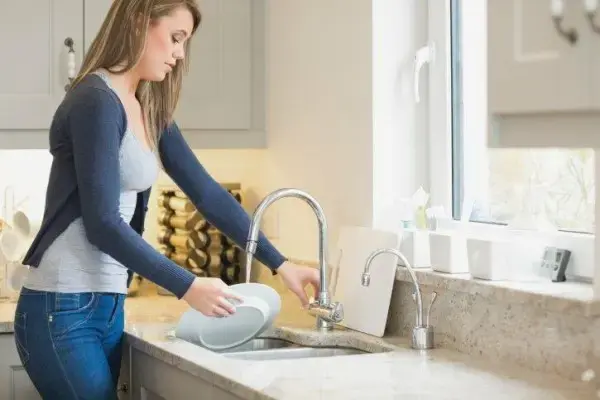 Torneira para cozinha: pessoa lavando a louça (foto: VIX)