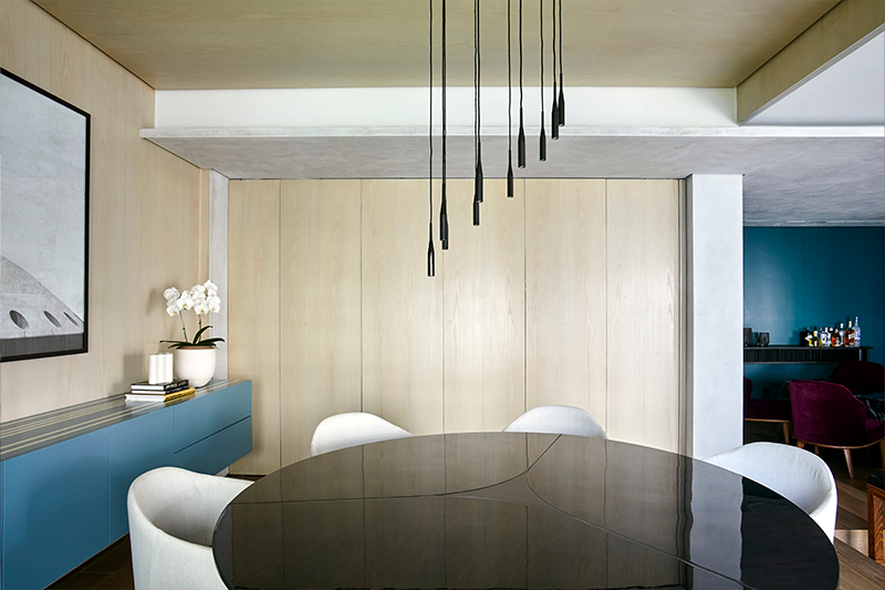 Projeto: Juliana Fabrizzi | Sala de jantar integrada à cozinha destaca o contraste entre a marcenaria clara, o azul-marinho dos armários e o design elegante do mobiliário.