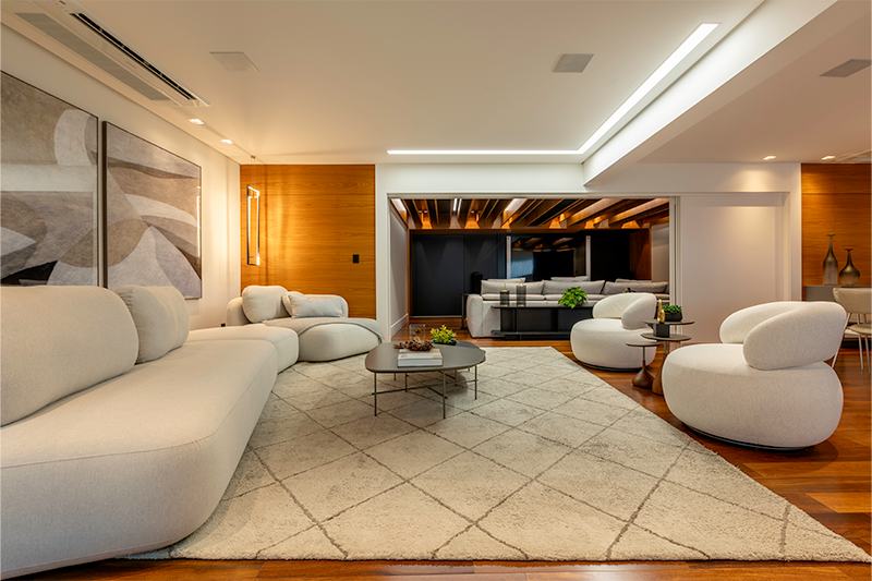 Portas e painéis de correr em marcenaria conectam salas e área gourmet, criando um espaço amplo para receber.