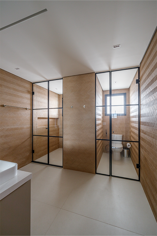 Projeto: Yannick Athia | Banheiros que se complementam: o principal, com duas cubas e cabines separadas; e o segundo, em tons de verde suave, traz leveza e continuidade ao projeto.