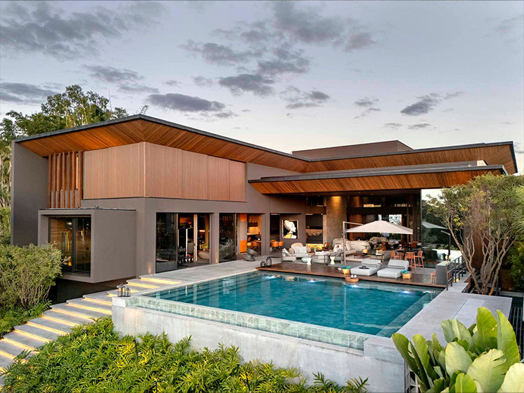 Projeto de arquitetura: Denise Zuba Arquitetos | Neste projeto, a vegetação foi cultivada de forma estratégica e em nível inferior ao da piscina para valorizar a vista panorâmico. Ao fundo, ao lado direito do deck, é possível observar uma árvore Pau Brasil com a função de trazer mais privacidade ao vizinho.