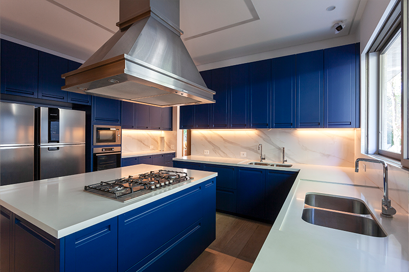 Projeto: BZP Arquitetura | Integrada às áreas sociais do térreo, a cozinha se destaca pela marcenaria em tom de azul, que adiciona personalidade à linguagem contemporânea do projeto