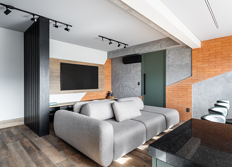 Projeto: Camila Palladino| O hall de entrada com luz lateral e divisória em madeira preta que introduz a paleta urbana e sofisticada do projeto ao entrar na sala