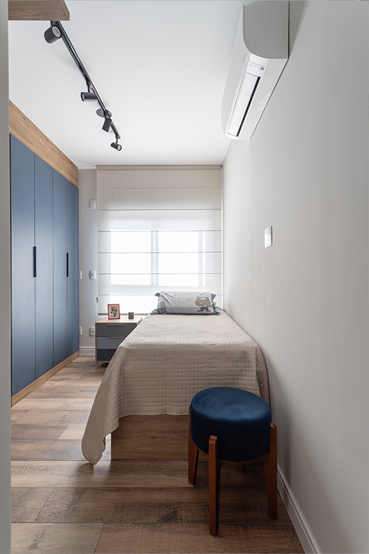 Projeto: Camila Palladino| Suíte funcional com home office: marcenaria contínua organiza bancada, armários e nichos; paleta em azul profundo, cinza e branco traz leveza e foco.