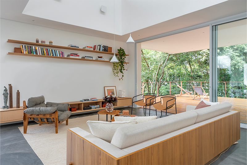 Super conectada à natureza, essa sala se abre para um deck de madeira e se projeta em direção a uma exuberante área verde.