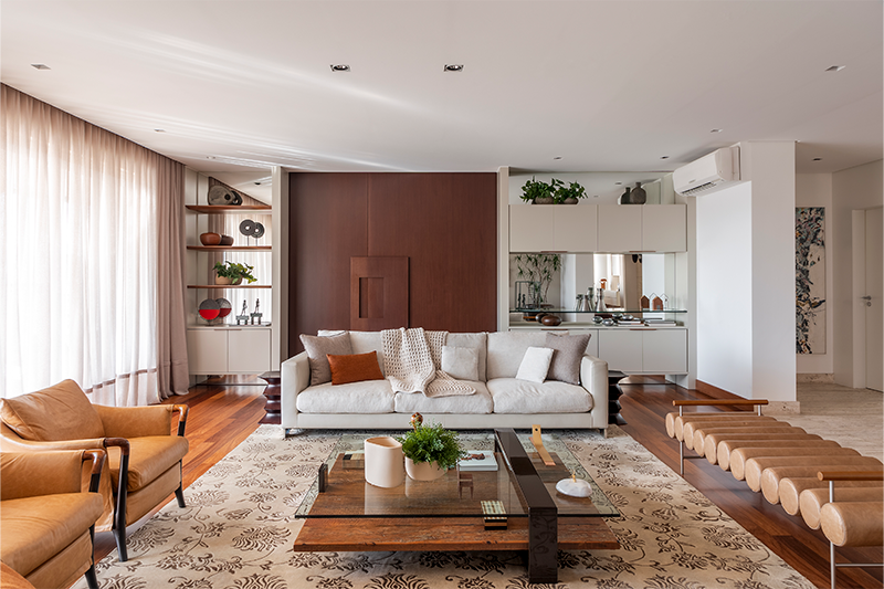 Nesse estar, o arquiteto Raphael Wittmann explorou o generoso espaço da sala com a disposição de sofá, uma dupla de poltronas e um banco. Ele se pautou no design das peças, como na alternância de cores que entregou uma elegância atemporal.
