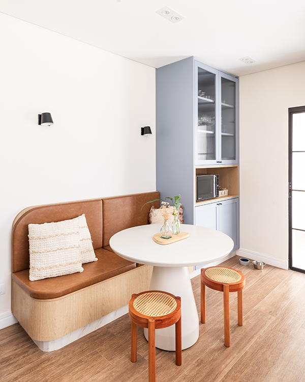 No entorno da pequena mesa redonda que demarca a pequena copa, o arquiteto Bruno Moraes incluiu um banco estofado acompanhado por dois charmosos banquinhos com assento em palhinha