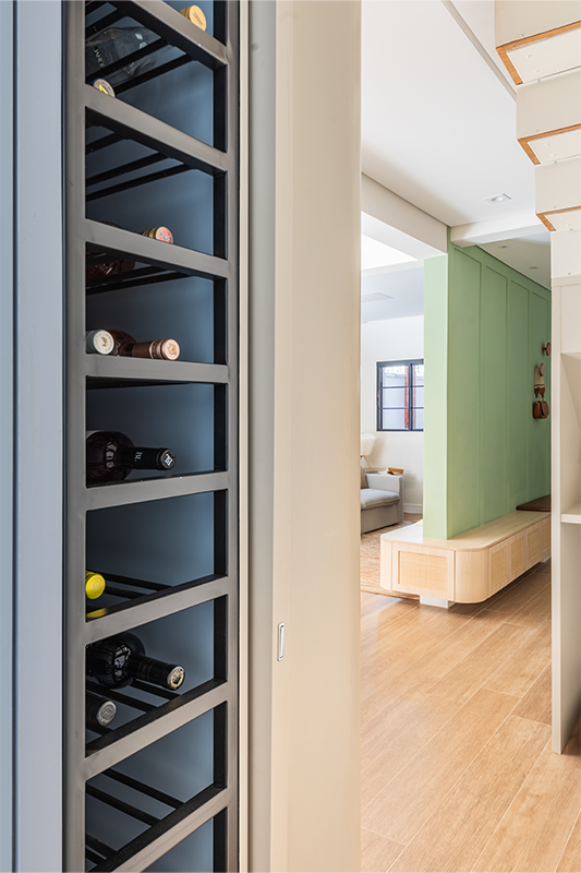 No limite da área, o projeto revela uma solução criativa para aproveitar um vão que ficaria sobrando: uma despretensiosa adega que acompanha o vão entre o piso e teto