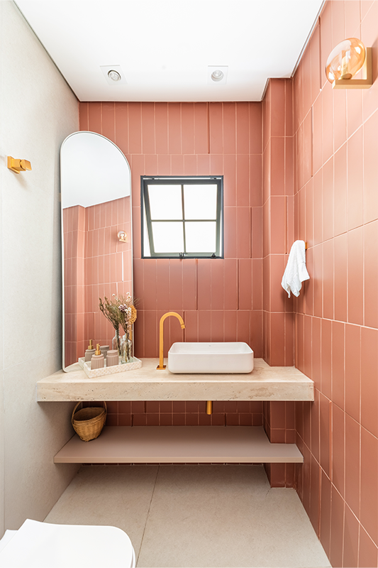 Já o lavabo se evidencia pela escolha do revestimento na paleta terracota, exalando um caráter caloroso e sofisticado ao ambiente