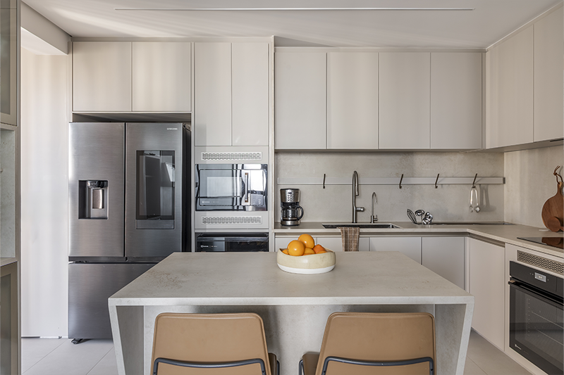 A disposição em 'L' otimiza a circulação, mantendo a cozinha funcional mesmo em espaço compacto