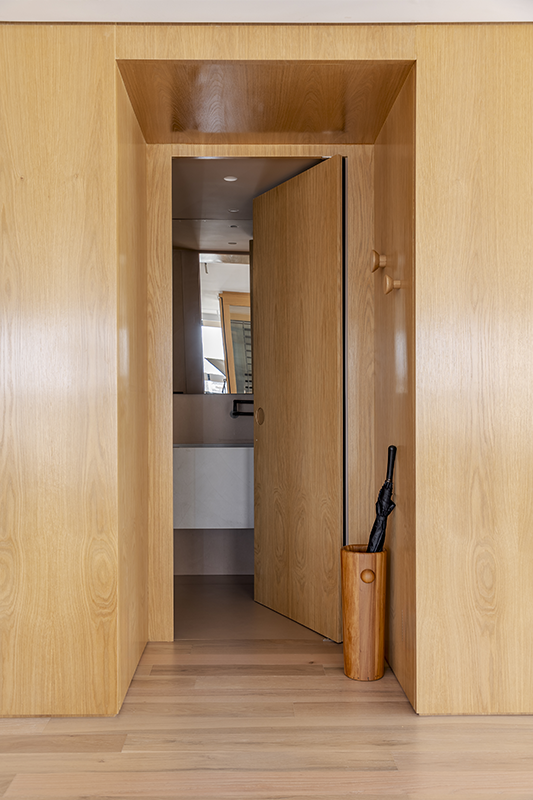 Discreto, o lavabo se esconde no painel de madeira