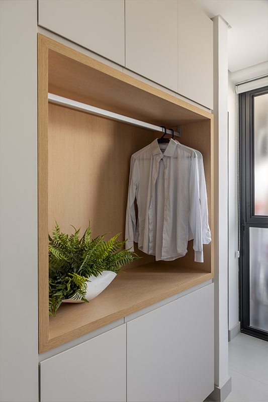 A lavanderia possui uma composição silenciosa de tons neutros, com desenho vertical das superfícies e nichos embutidos na marcenaria para criar ambiente ordenado