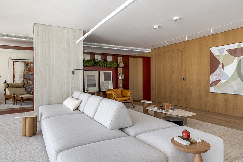 A marcenaria advém do hall e segue em painéis contínuos que acomodam uma pintura exclusiva de Ronald Lago