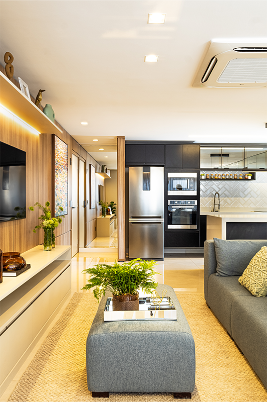 O sofá no centro organiza e conecta: estar, jantar e área gourmet se encontram em um layout fluido e funcional.