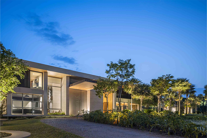 Assim como no espaço de lazer, voltado para o fundo da casa, a área que contempla a frente e as laterais da residência também apresenta variedade de espécies, como carandás e Thaumatophyllum jobim, com um belo jardim e um clima de reconexão com a natureza, que encanta os visitantes logo ao chegar ao local